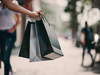 Close up of woman`s hand holding shopping bags while walking on the street.